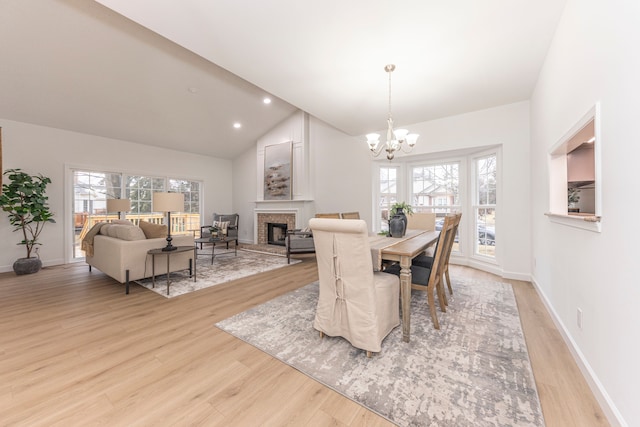 dining area with lofted ceiling, recessed lighting, a fireplace, a notable chandelier, and light wood-type flooring