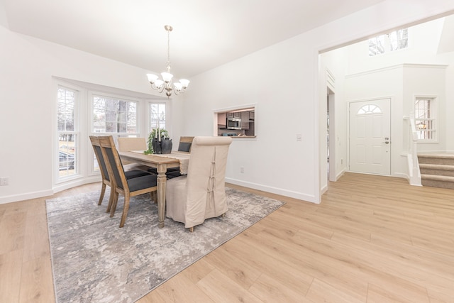 dining space featuring light wood-style flooring, baseboards, stairs, and an inviting chandelier