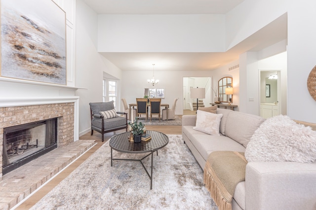 living area with baseboards, a fireplace, a high ceiling, wood finished floors, and a notable chandelier