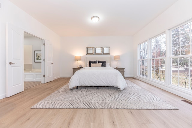 bedroom featuring light wood finished floors, visible vents, and baseboards