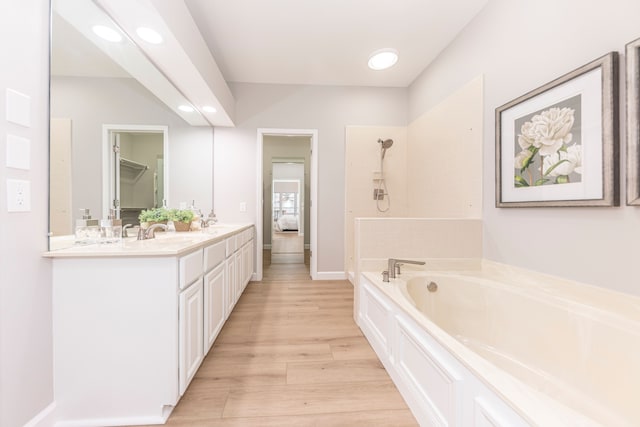 full bath featuring wood finished floors, double vanity, a sink, walk in shower, and a garden tub