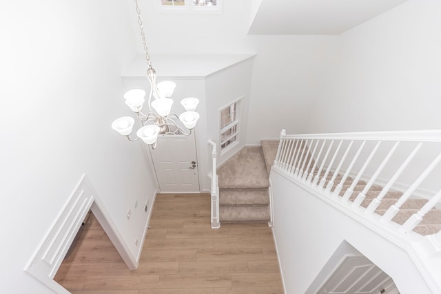 stairs with an inviting chandelier and wood finished floors