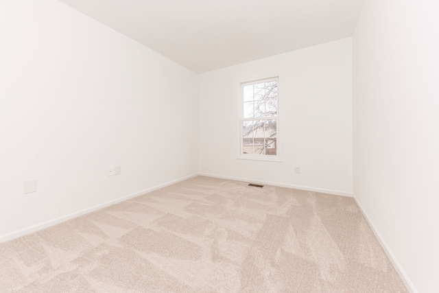 empty room featuring visible vents, baseboards, and light carpet