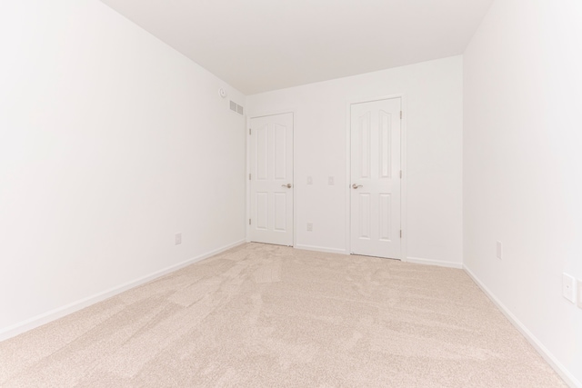 unfurnished bedroom with visible vents, light colored carpet, and baseboards