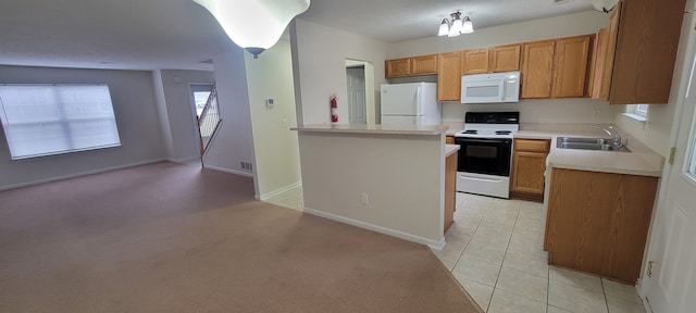 kitchen featuring white appliances, brown cabinets, light countertops, a sink, and light tile patterned flooring