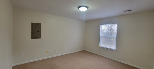 spare room featuring baseboards, electric panel, visible vents, and light colored carpet