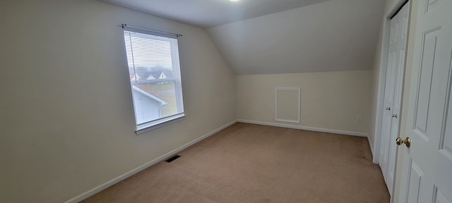 bonus room featuring lofted ceiling, baseboards, visible vents, and light colored carpet