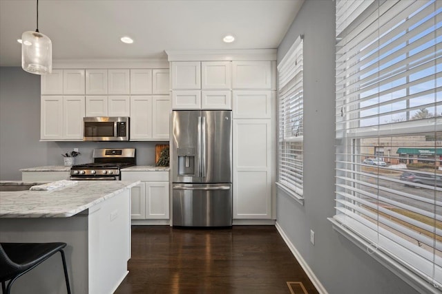 kitchen with dark wood-style floors, hanging light fixtures, appliances with stainless steel finishes, white cabinetry, and baseboards