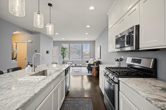 kitchen featuring stainless steel appliances, dark wood-type flooring, a sink, white cabinetry, and open floor plan