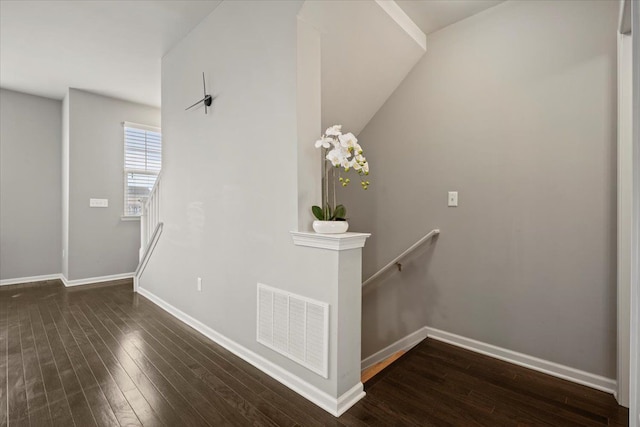 staircase with baseboards, visible vents, and wood finished floors