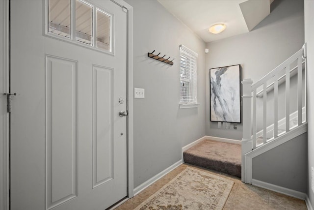 entrance foyer with stairs, baseboards, and tile patterned floors