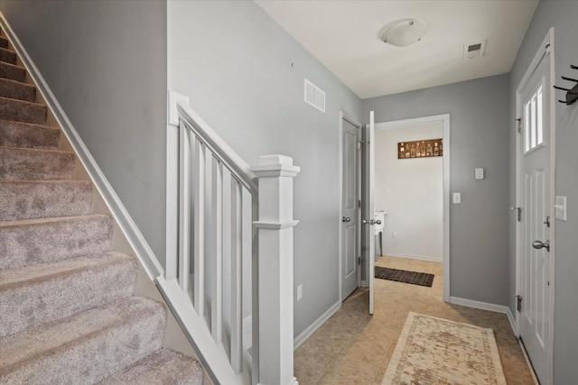 foyer featuring baseboards, stairs, and visible vents