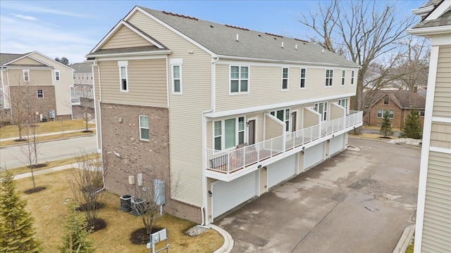 back of property featuring central AC, aphalt driveway, and brick siding