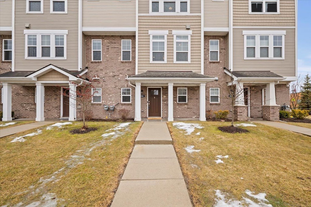 townhome / multi-family property featuring brick siding and a front lawn