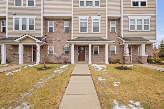 townhome / multi-family property featuring brick siding and a front lawn