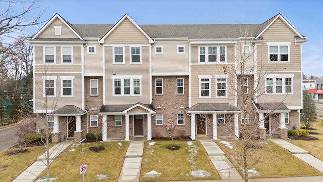 townhome / multi-family property featuring brick siding and a front lawn