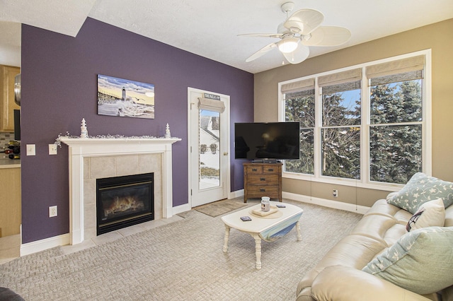 living room featuring a ceiling fan, a tile fireplace, and baseboards