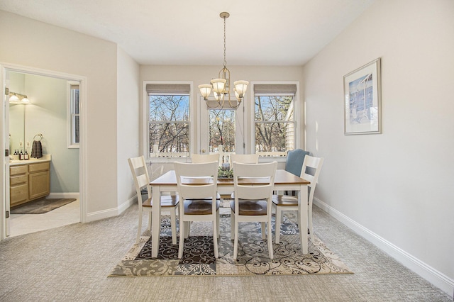 dining area with an inviting chandelier, baseboards, and light colored carpet