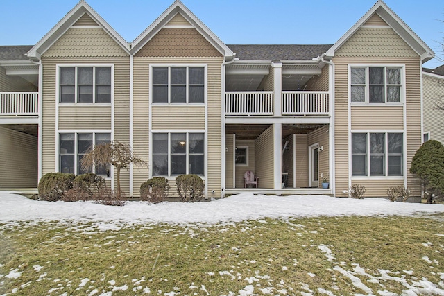 snow covered rear of property featuring a balcony