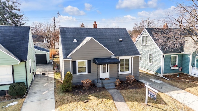 view of front of house with a shingled roof, a detached garage, and a chimney