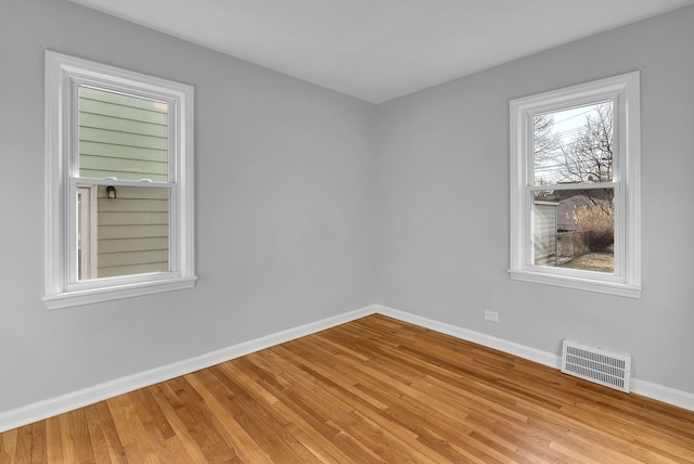 empty room with light wood-style flooring, visible vents, and baseboards