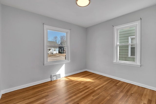 empty room featuring baseboards, visible vents, and wood finished floors