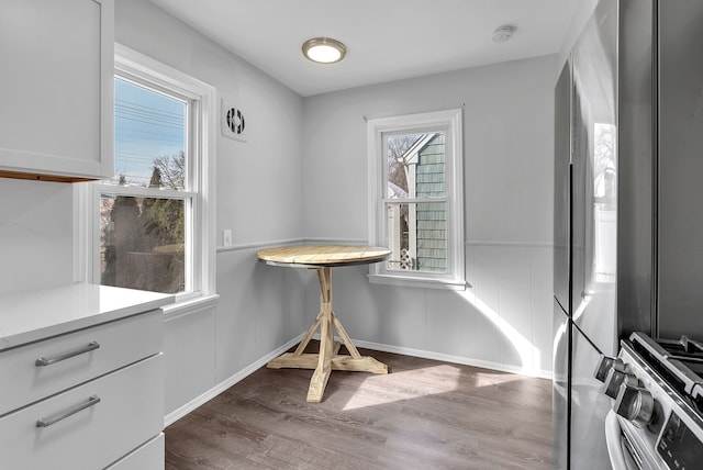 dining area with baseboards, dark wood-type flooring, and wainscoting