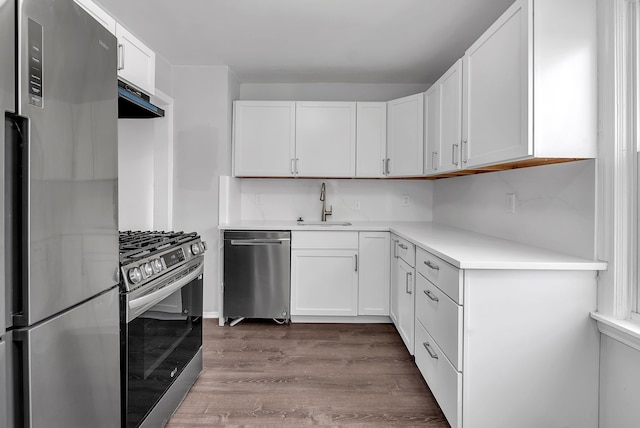 kitchen featuring white cabinets, dark wood-style floors, appliances with stainless steel finishes, light countertops, and a sink