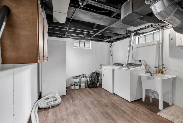 laundry area featuring wood finished floors, cabinet space, a sink, and separate washer and dryer