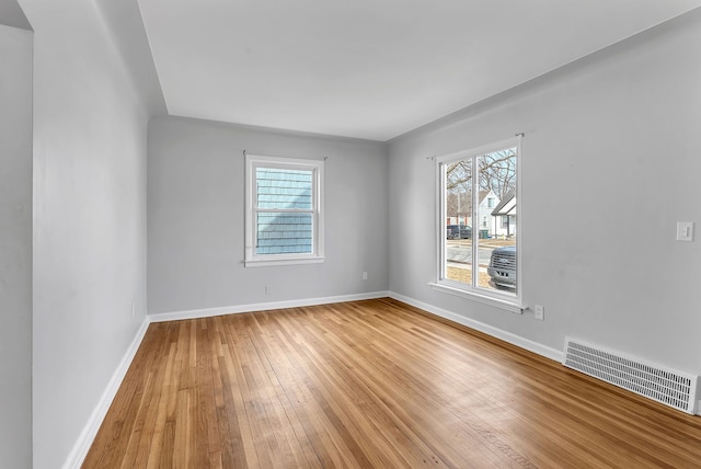 empty room featuring hardwood / wood-style flooring, baseboards, and visible vents