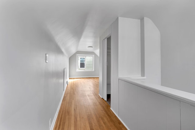 hall featuring vaulted ceiling, baseboards, and wood finished floors