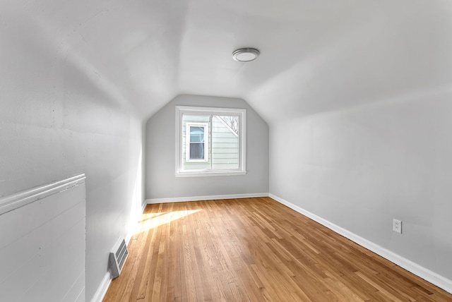 additional living space with lofted ceiling, light wood-style flooring, visible vents, and baseboards