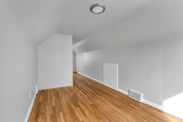 bonus room featuring light wood-type flooring, baseboards, visible vents, and vaulted ceiling