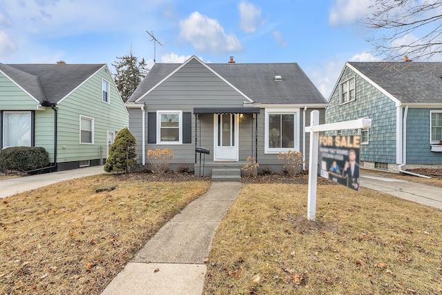 bungalow featuring a shingled roof, a chimney, and a front lawn