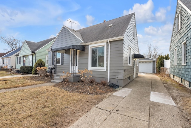 bungalow featuring roof with shingles, a detached garage, and an outbuilding