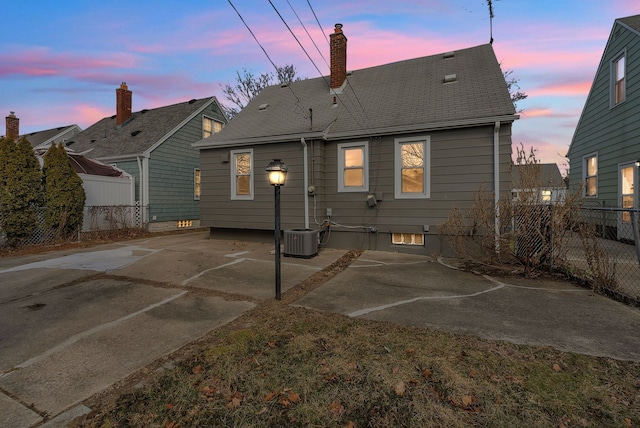 rear view of property featuring a patio area, fence, a chimney, and roof with shingles