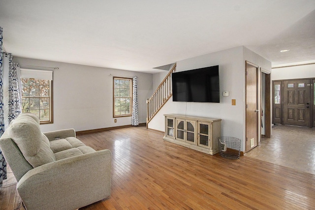 living room featuring wood-type flooring, baseboards, and stairs