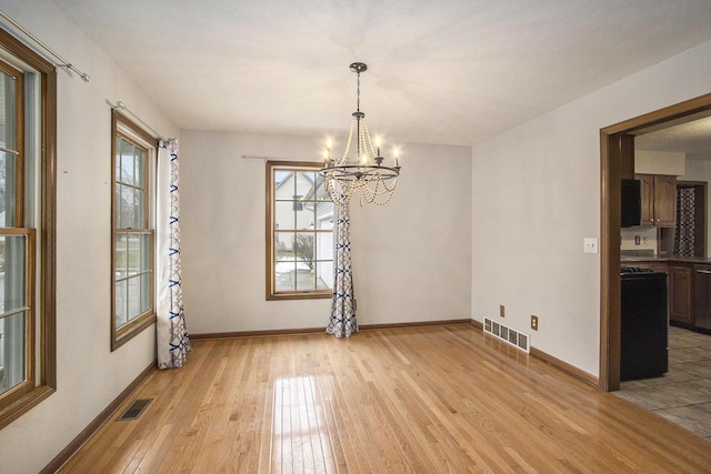 unfurnished dining area featuring light wood-style flooring, visible vents, and baseboards