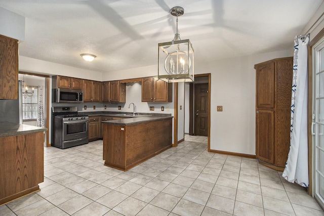 kitchen featuring a notable chandelier, dark countertops, appliances with stainless steel finishes, a sink, and a peninsula