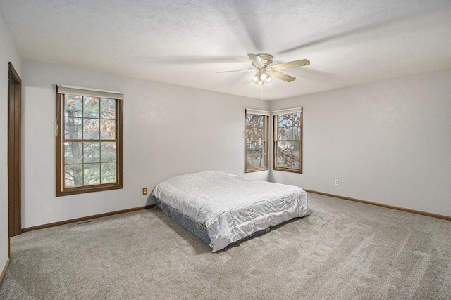 bedroom featuring a textured ceiling, carpet, a ceiling fan, and baseboards