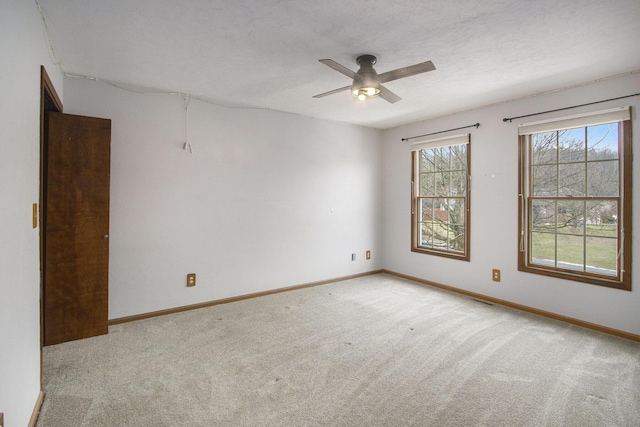 carpeted empty room featuring a textured ceiling, ceiling fan, and baseboards