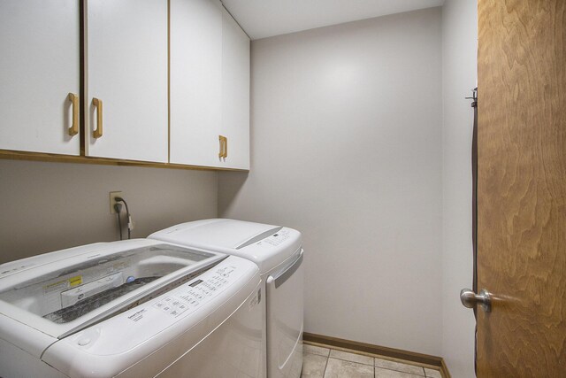 washroom featuring cabinet space, washing machine and dryer, baseboards, and light tile patterned flooring