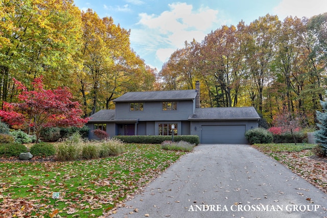 view of front of house featuring driveway, a chimney, and an attached garage