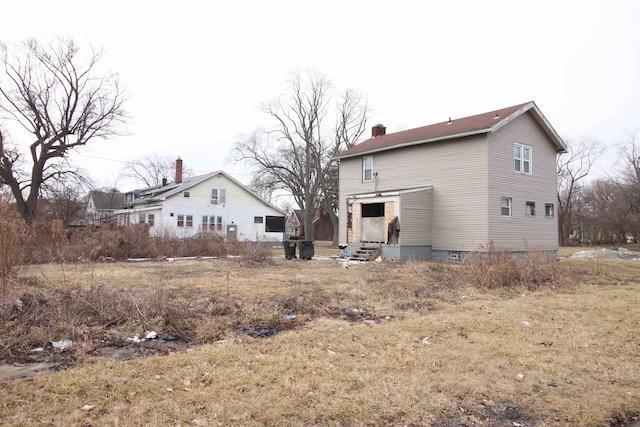 back of property with entry steps and a chimney