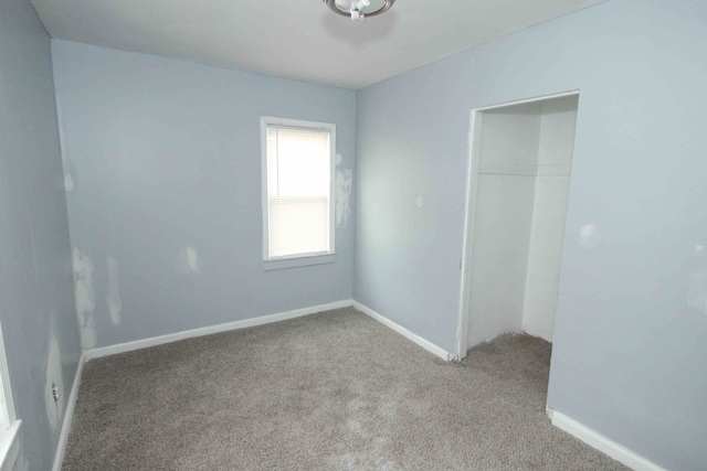 carpeted empty room featuring baseboards