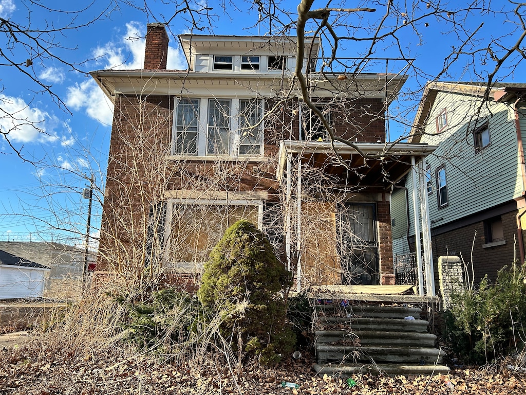 view of front of home with a chimney and brick siding