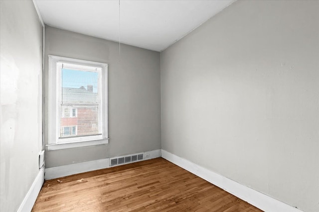 unfurnished room featuring wood finished floors, visible vents, and baseboards