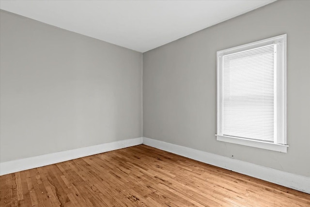 spare room featuring wood-type flooring and baseboards