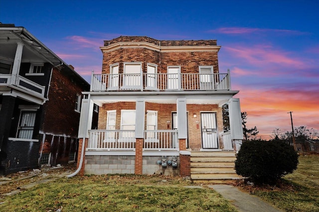 view of front of property with a balcony, a porch, and brick siding