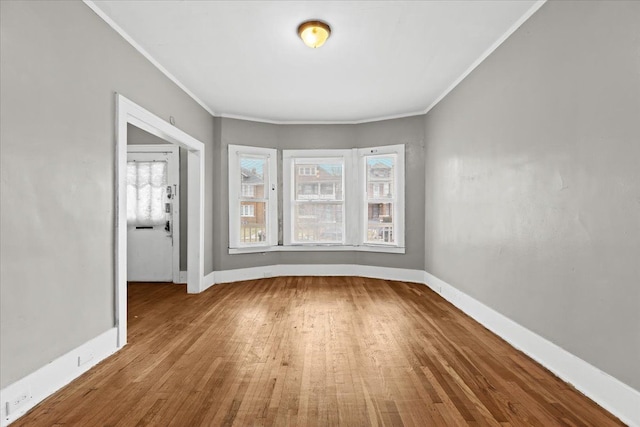 spare room featuring ornamental molding, wood finished floors, and baseboards